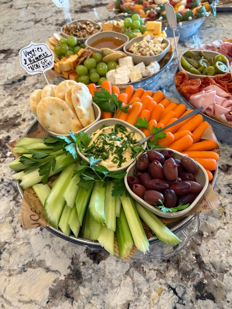 Veggies and hummus platter with celery, carrots, olives, and pita.