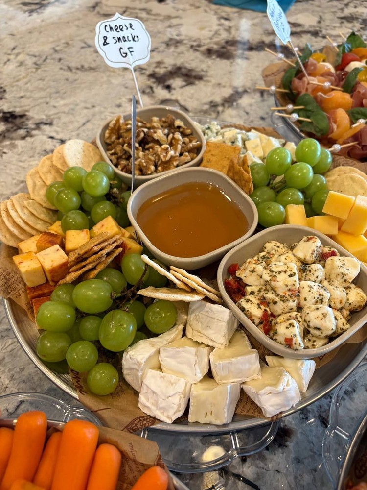 Cheese and snack platter with grapes, crackers, nuts, and brie.
