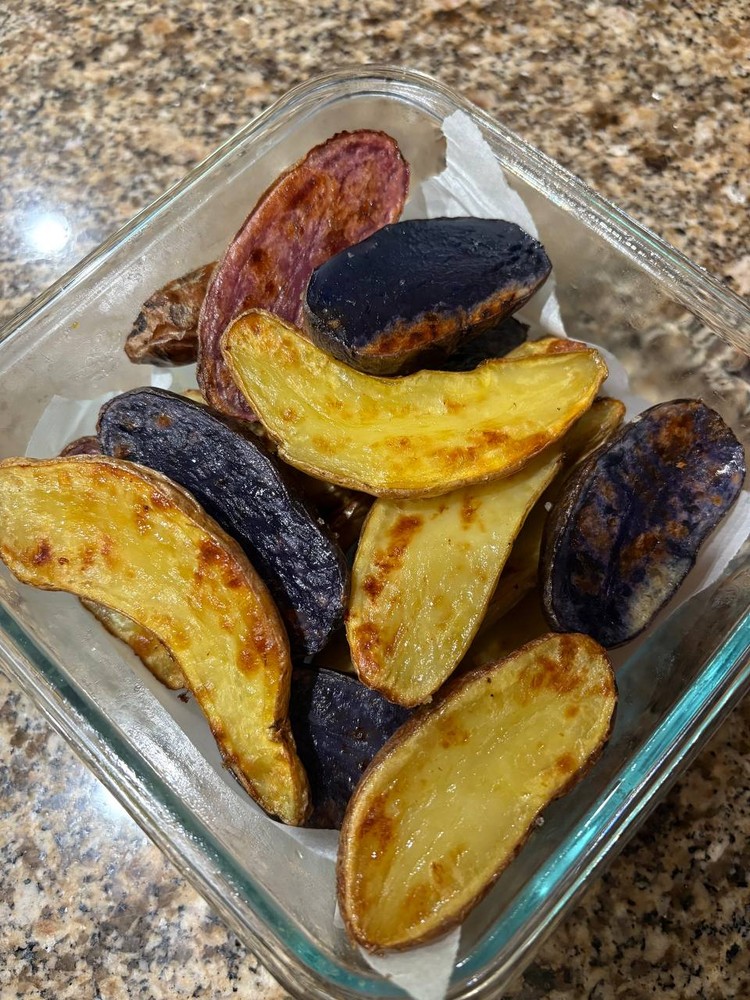 Roasted purple and yellow potato wedges in a glass dish
