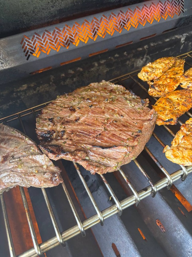 Steak and chicken cooking on a hot grill