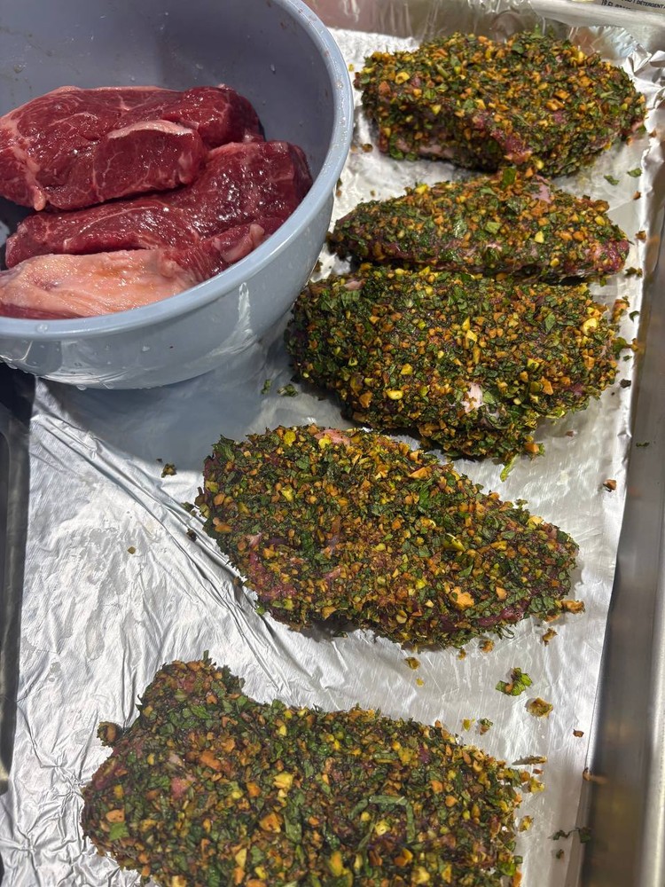 Raw beef steaks coated in a green herb and nut crust