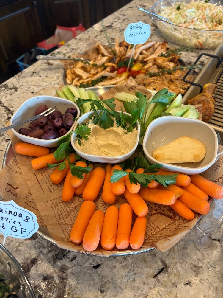 Hummus and vegetable platter with carrots, celery, and olives.