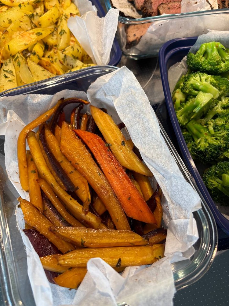 Roasted colorful carrots in a glass meal prep container.