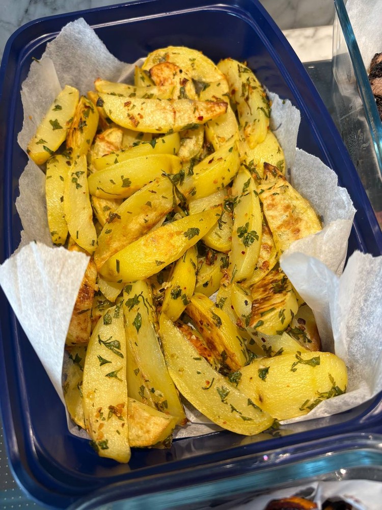 Herb-roasted potato wedges in a blue meal prep container.