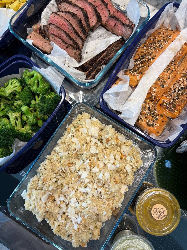 Close-up of coconut quinoa, sliced steak, and salmon in meal prep containers.