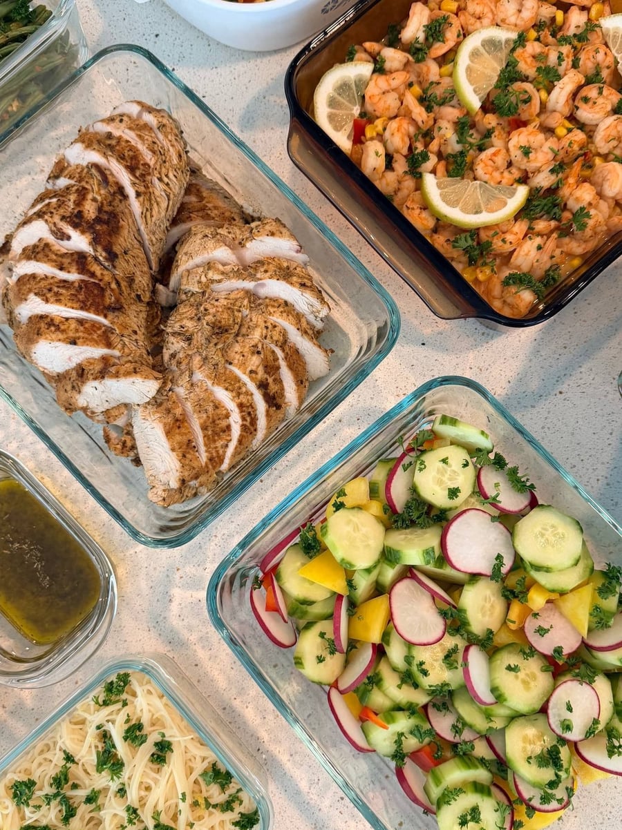 Shrimp and sweet corn share a smoky brown dish, lemon wheels on top, cucumber radish salad beside.