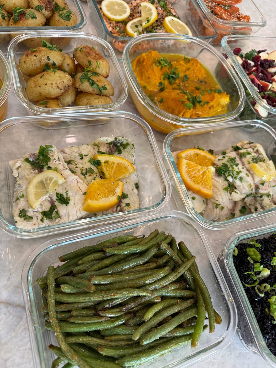 Orange and lemon wedges rest on white barramundi fillets flecked with chopped parsley, green beans below.
