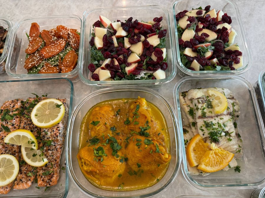 Turmeric sauce pools around chicken thighs, with apple, dried cranberry and kale in the dish alongside.