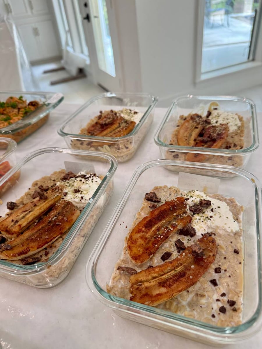 Caramelized banana halves and chocolate shards top four bowls of protein oatmeal under whipped yogurt.