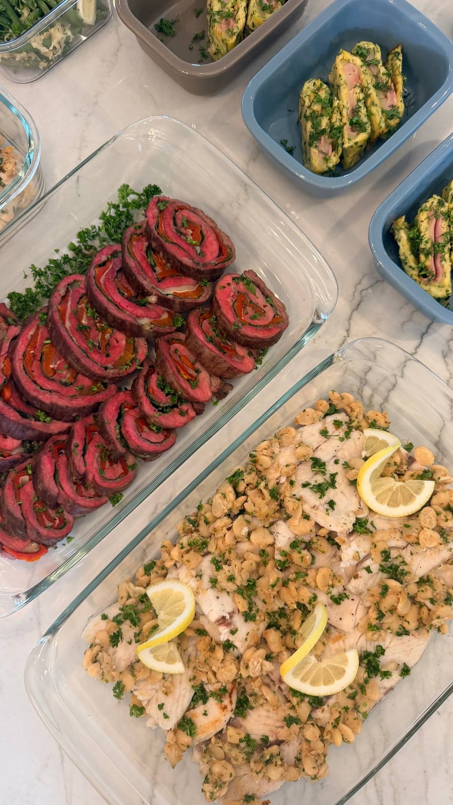 Lemon wheels press into barramundi and butter beans, steak pinwheels stacked in the next tray.
