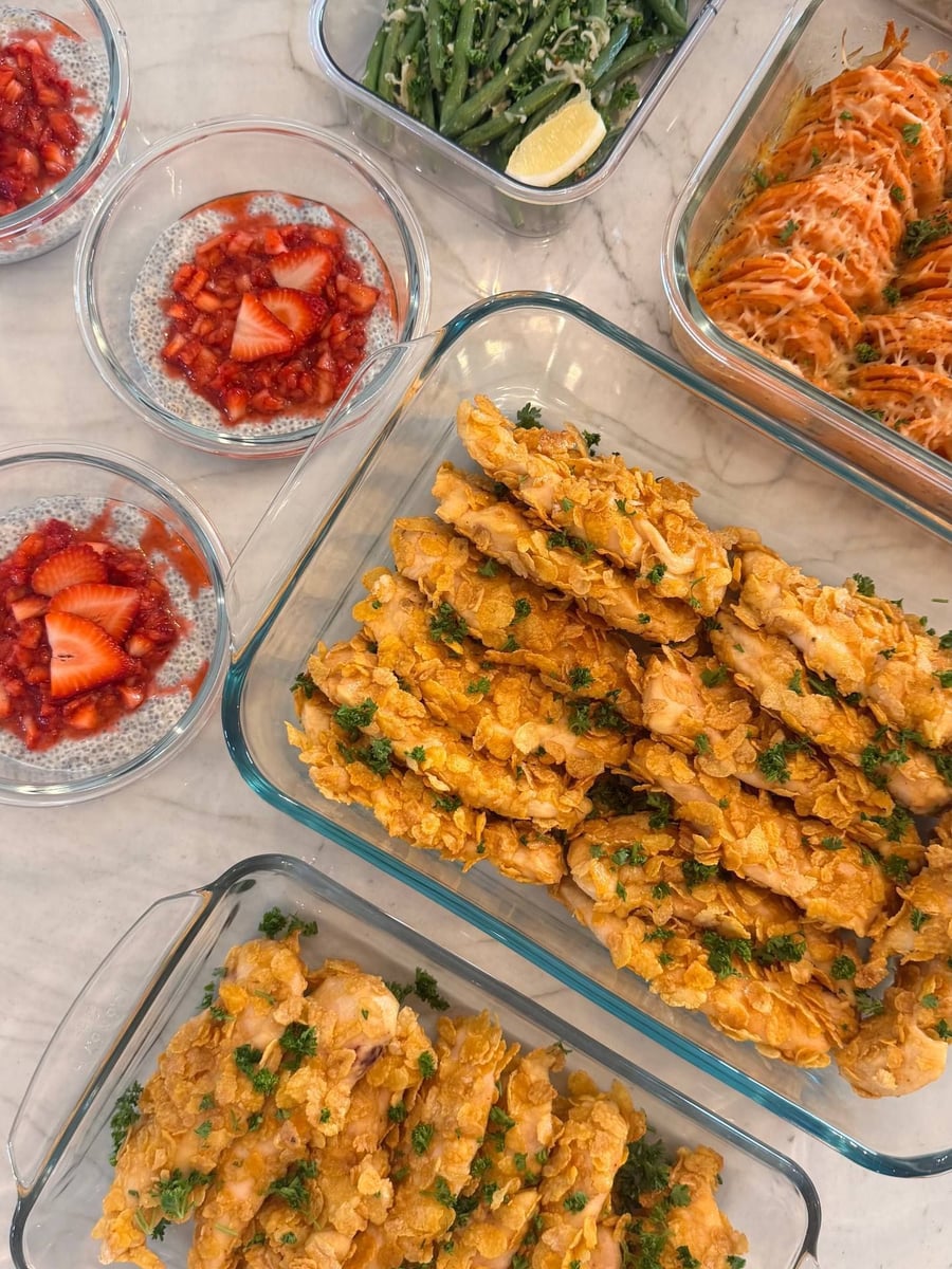 Cornflake crust shatters over baked chicken tenders, strawberry chia puddings and cajun sweet potato behind.