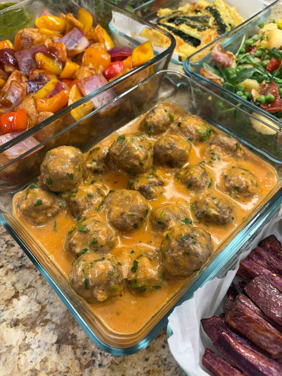 Stroganoff meatballs sit in a creamy orange sauce, sweet and sour chicken and purple potato fries alongside.