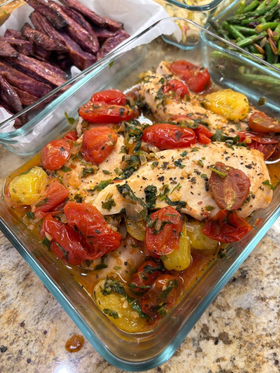 Burst cherry tomatoes in red and yellow surround braised chicken pomodoro, basil worked through the juices.