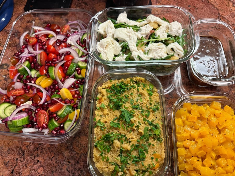 Pomegranate seeds scatter through cucumber, cherry tomatoes and red onion, couscous and gnocchi below.