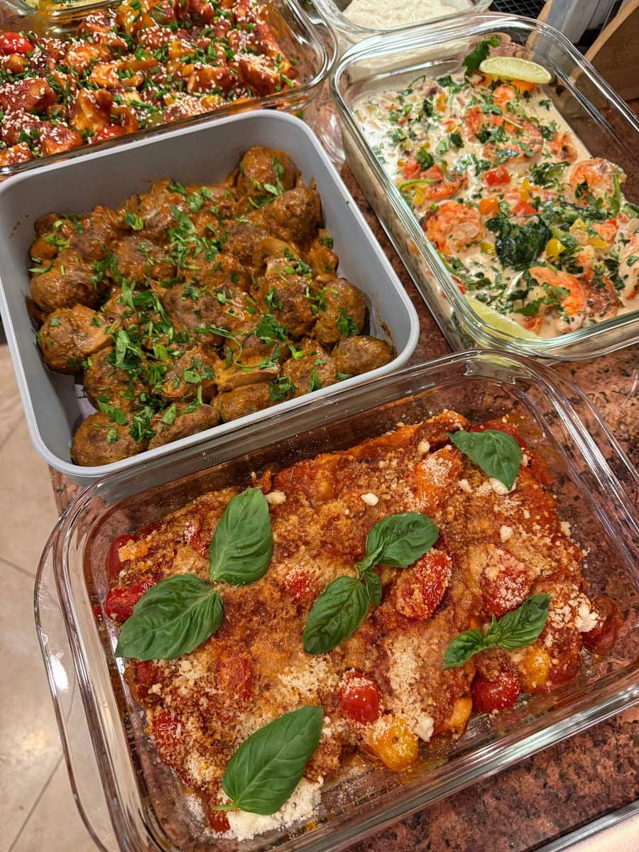 Basil leaves crown chicken pomodoro under grated parmesan, stroganoff meatballs and coconut shrimp nearby.