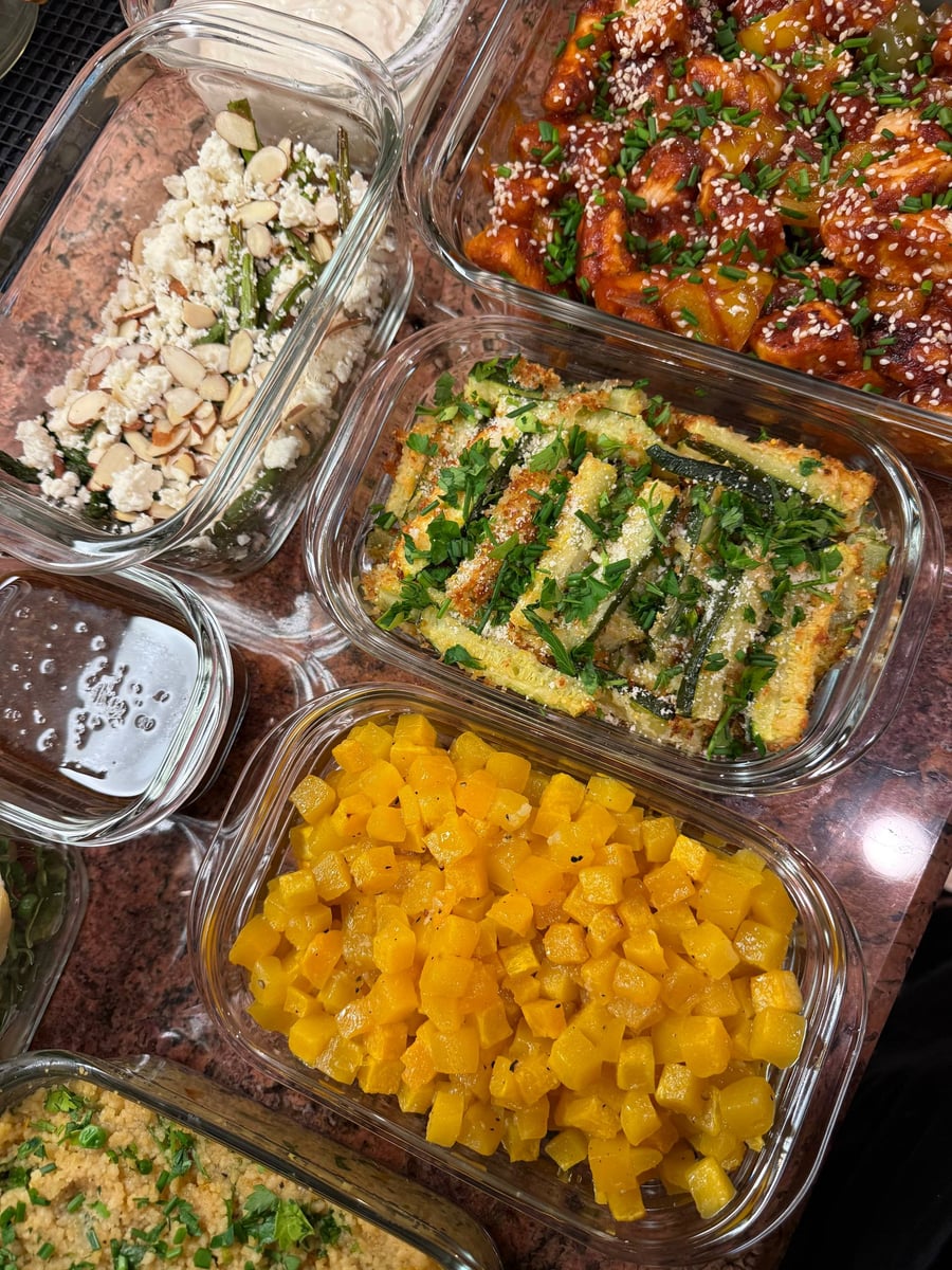 Diced butternut squash glazed with maple fills one tub, zucchini sticks and feta-topped asparagus above.