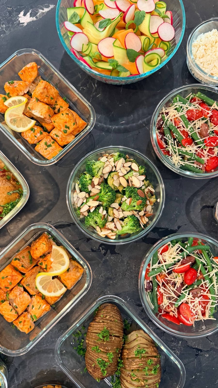 Chili almonds pile over broccoli, with green beans, cherry tomatoes, olives and shaved Asiago in the bowls around.