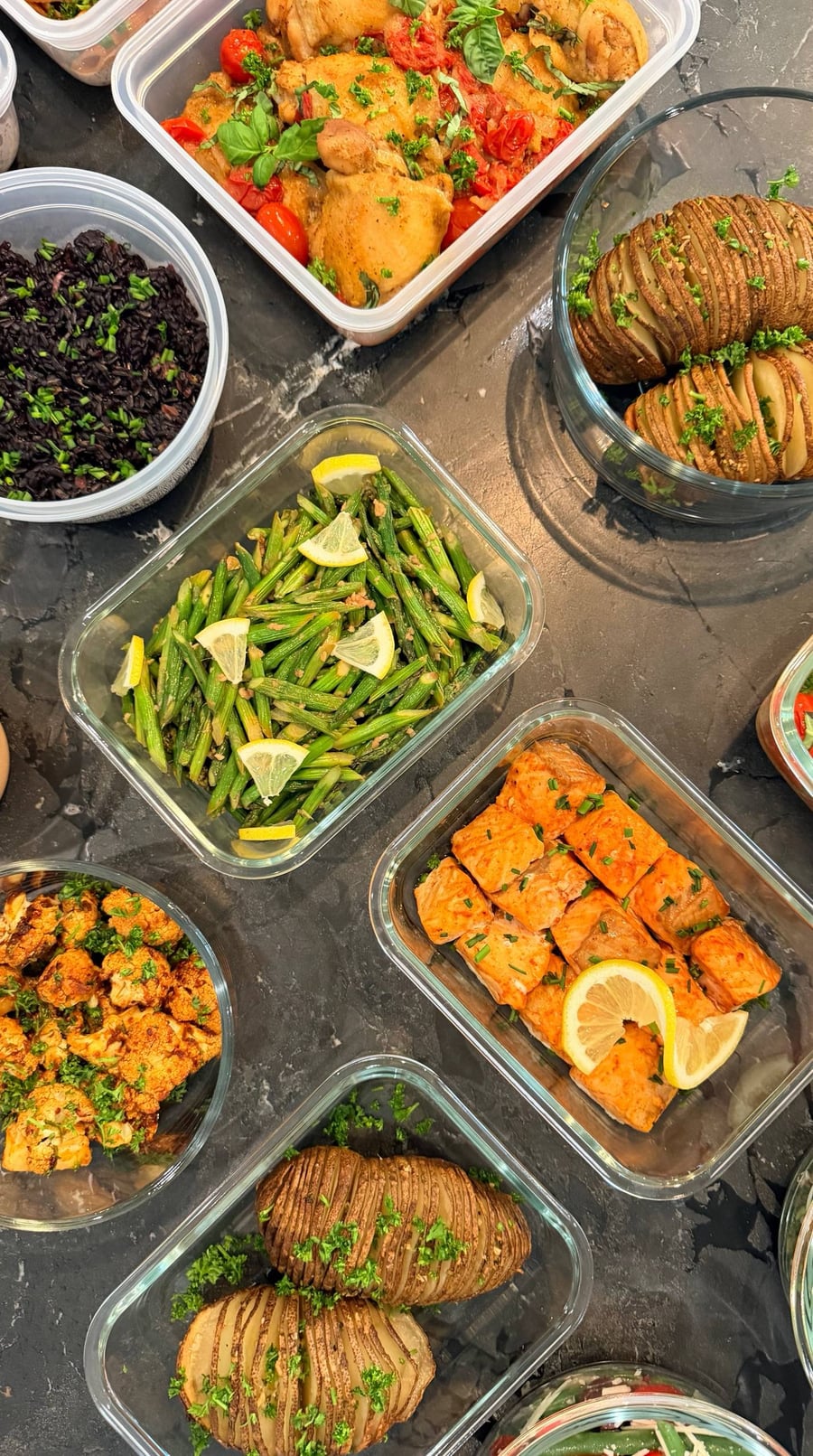 Asparagus tips and cut stalks glisten with garlic, lemon wedges tucked between them in a square dish.
