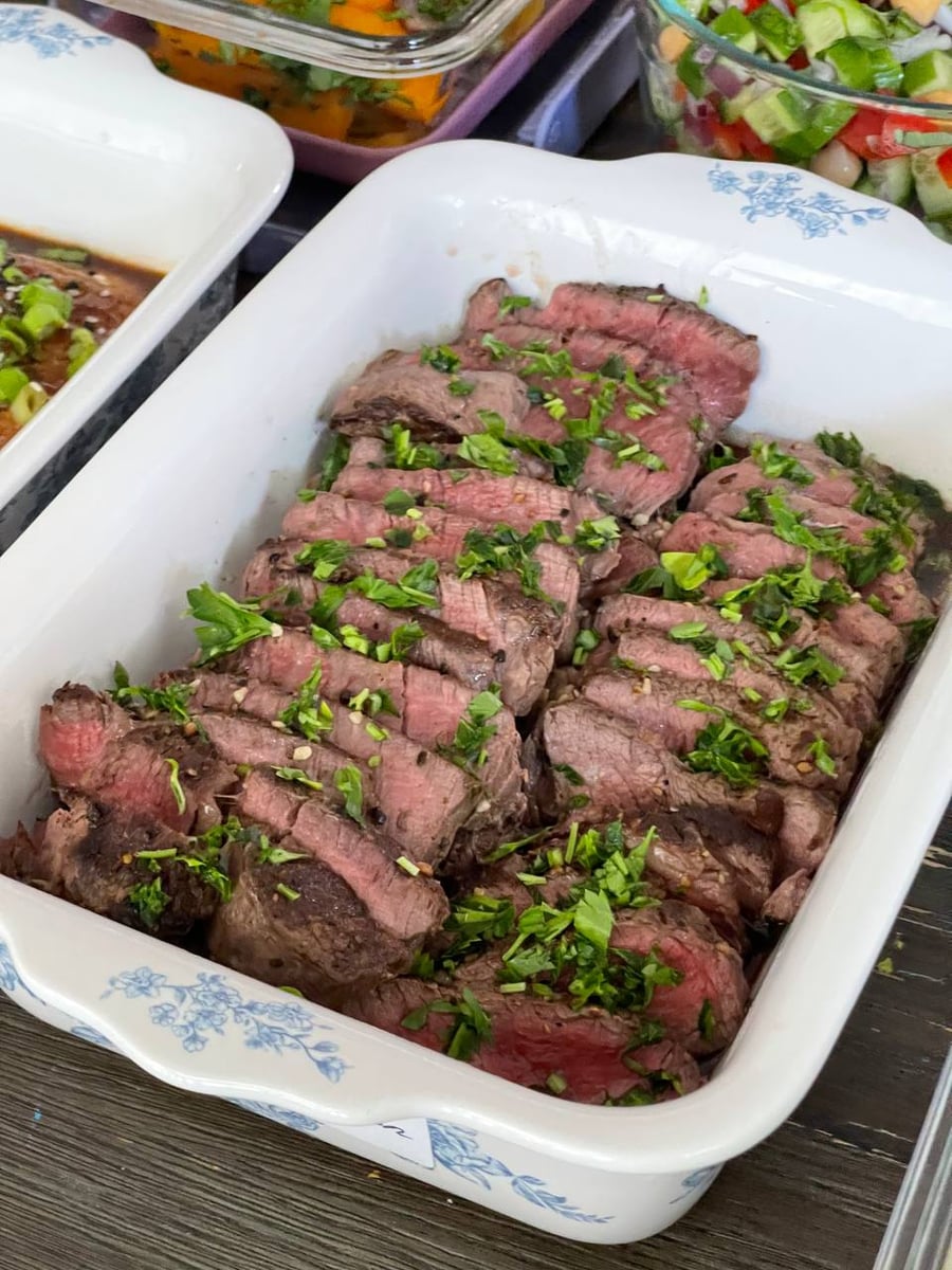 Pink centres run the length of every filet mignon slice, chopped parsley and garlic scattered across the dish.
