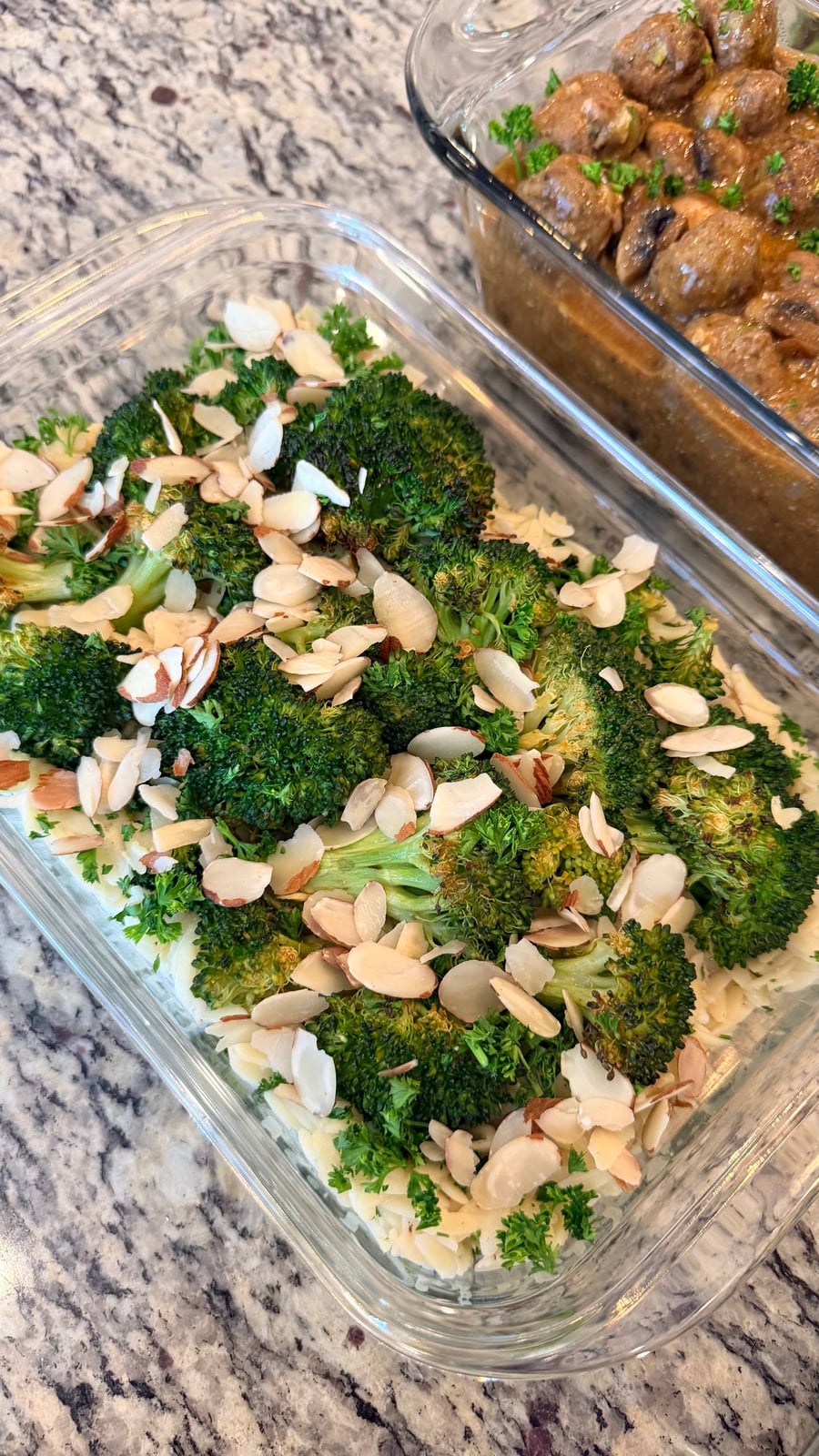 Sliced almonds cover roasted broccoli on a bed of orzo, stroganoff meatballs in gravy behind.