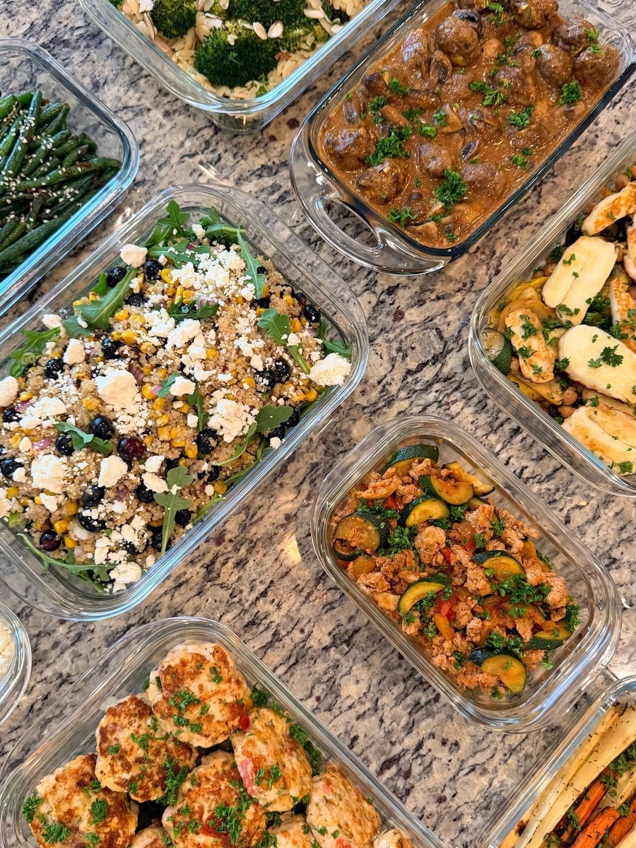 Parsley flecks pale chicken patties studded with tomato, quinoa salad and stroganoff filling the counter above.