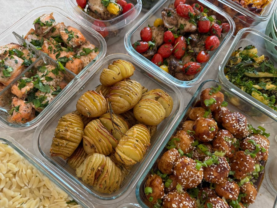 Scallions and sesame cover glazed chicken meatballs, hasselback potatoes and garlic salmon bites below them.