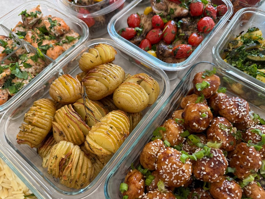 Hasselback potatoes fan open around a rosemary sprig, glazed chicken meatballs and salmon bites either side.