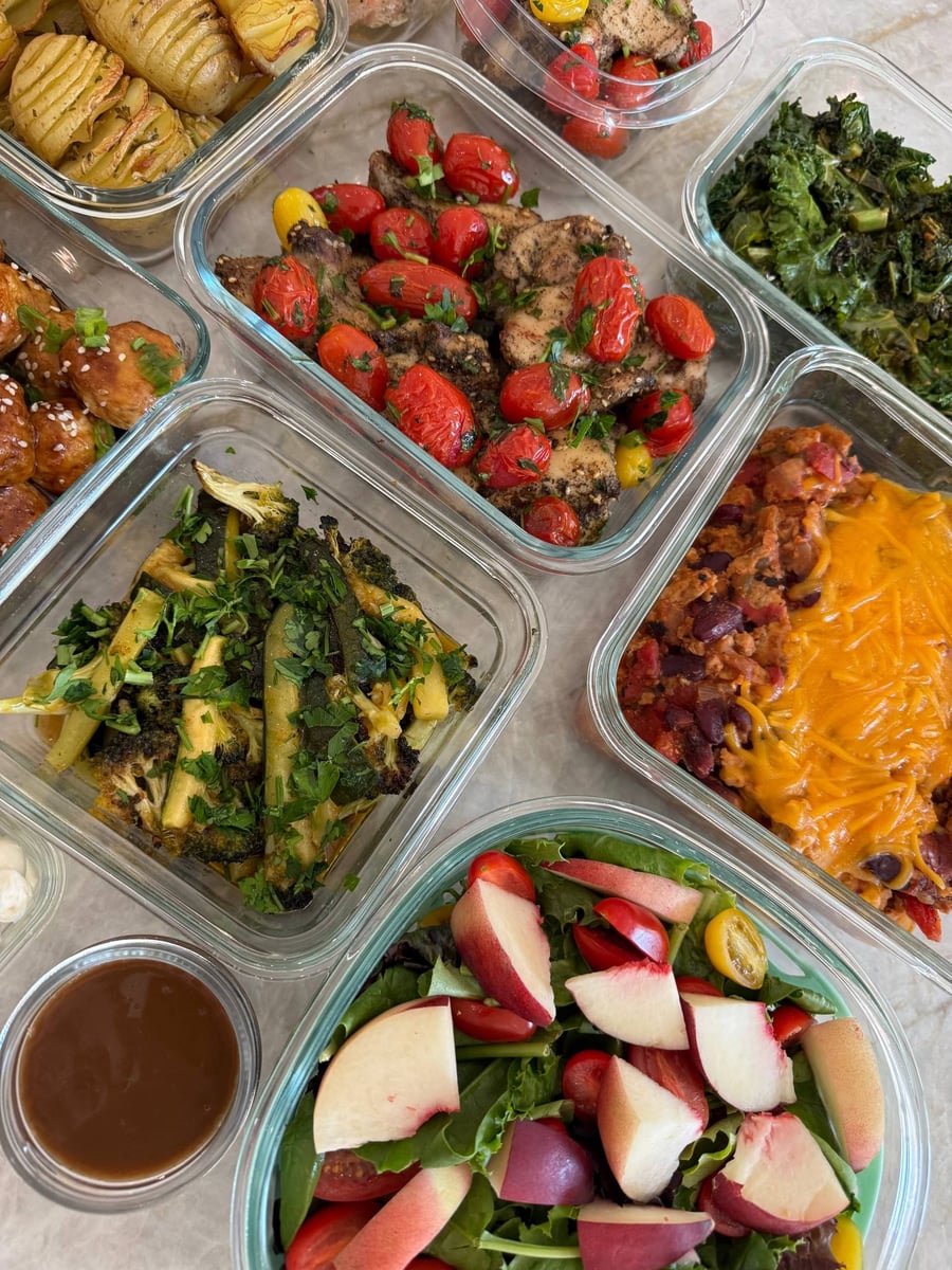 Peach wedges and cherry tomatoes lie across leafy greens, cheddar-topped turkey chili and kale behind them.