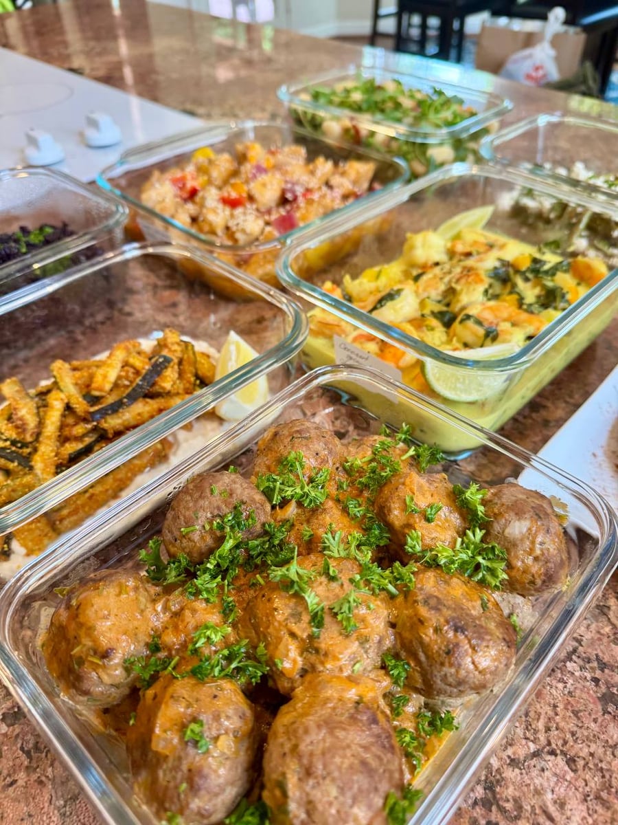 Curly parsley heaps over beef stroganoff meatballs in a thin gravy, zucchini sticks to the left.