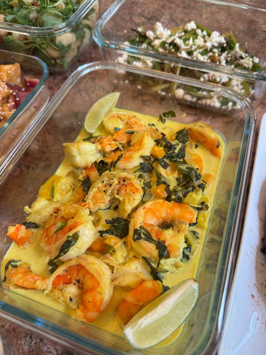 Shrimp curl through a yellow coconut sauce with wilted spinach and lime, asparagus and feta above.