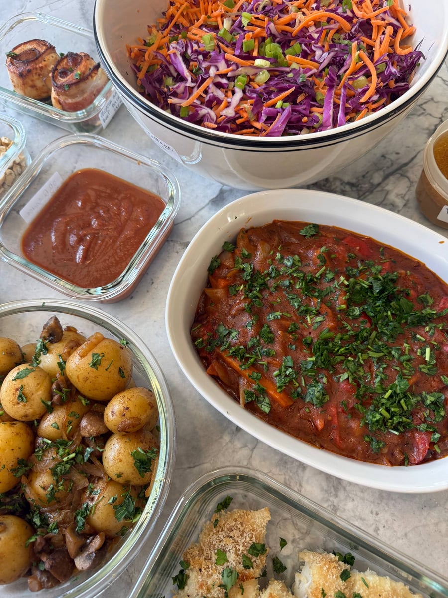 Shredded purple cabbage, carrot and scallion fill a rimmed white bowl beside the bbq sauce and stew.