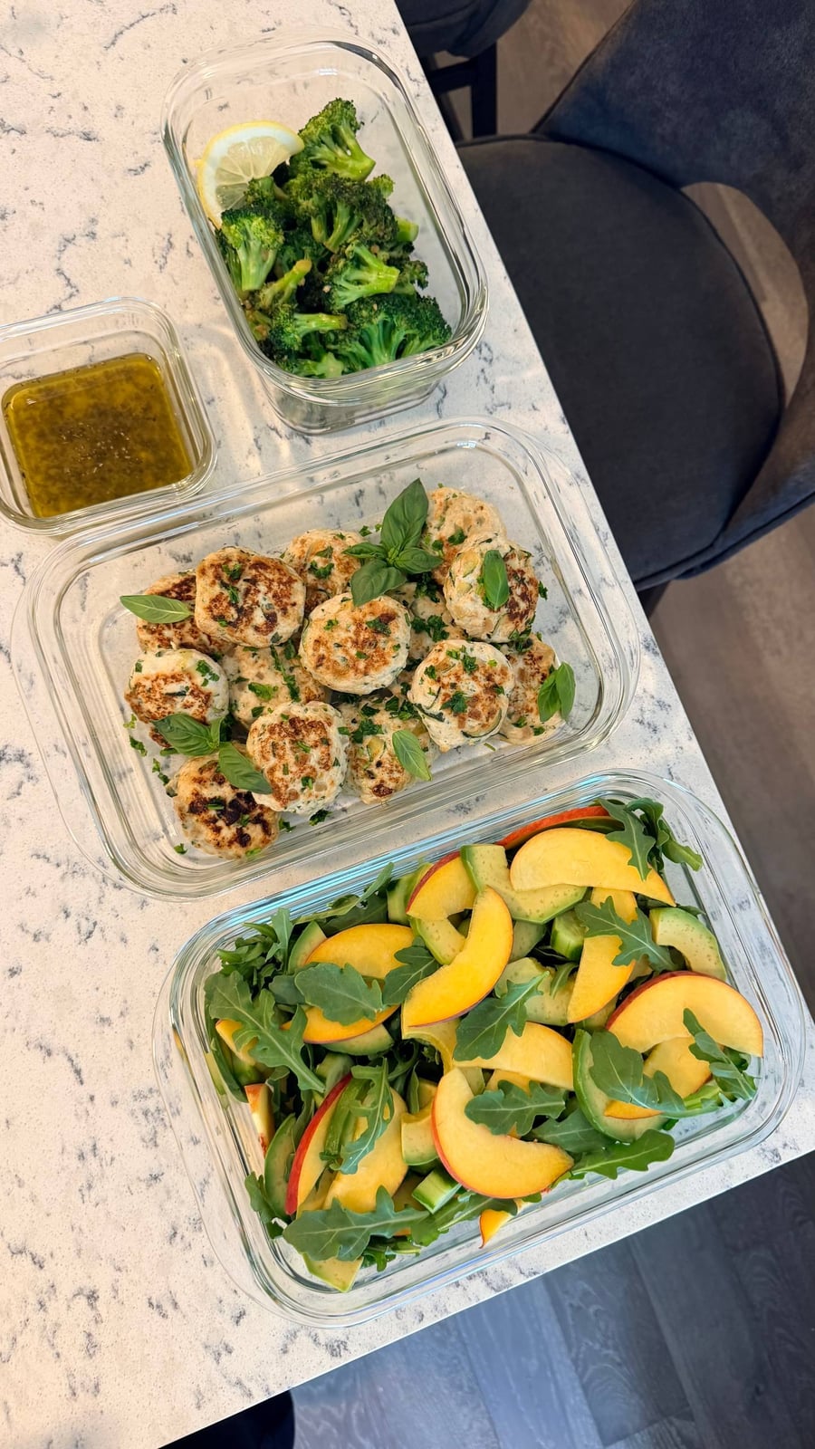Whole basil tops the seared chicken patties, with peach, avocado and cucumber layered through arugula beside them.