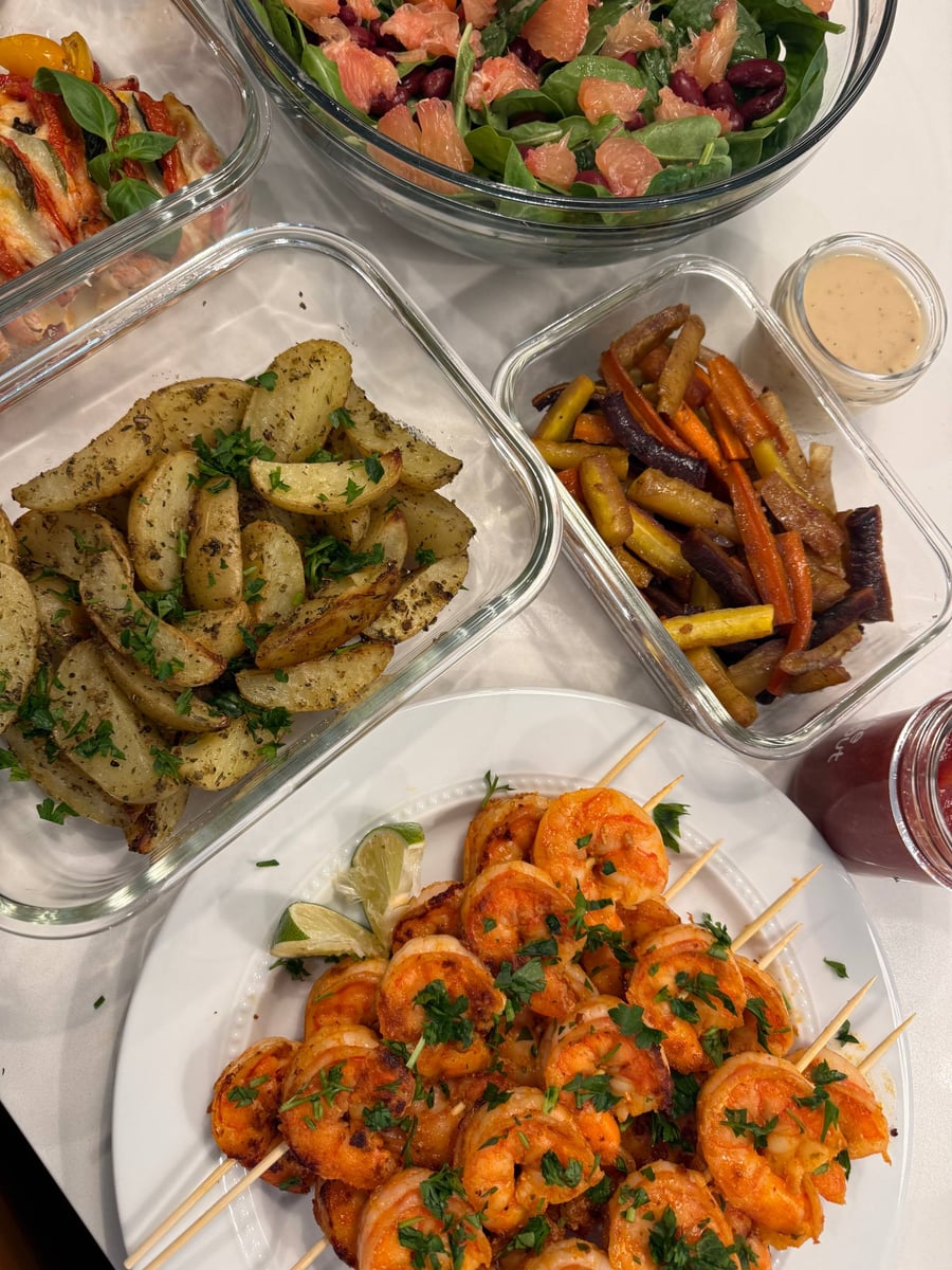 Oregano and parsley cling to thick potato wedges, rainbow carrots and the shrimp skewer plate alongside.
