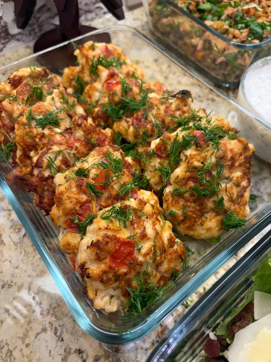 Dill fronds cover chicken patties studded with tomato and mozzarella, yogurt dip waiting to the right.