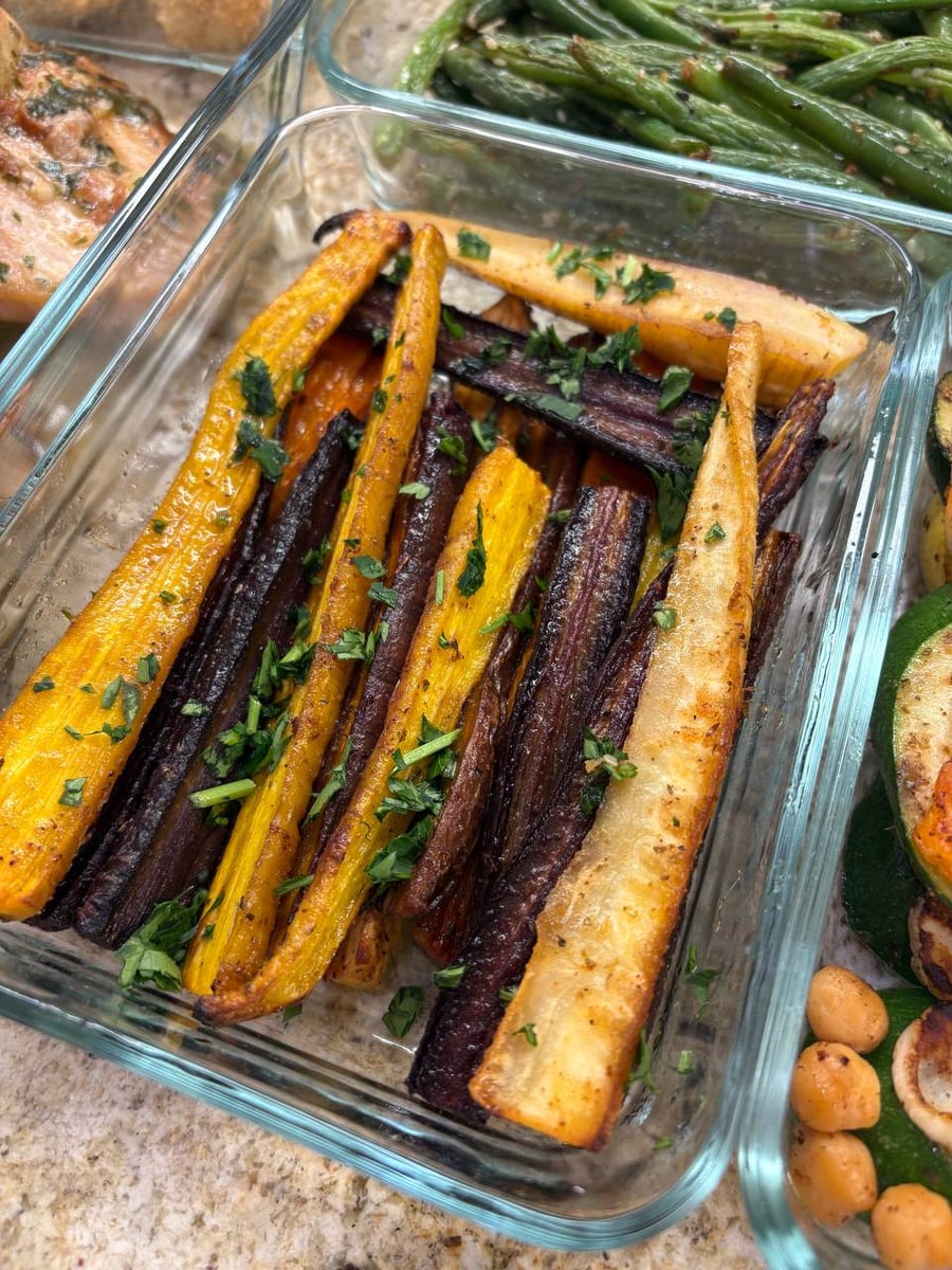 Yellow, purple and cream carrots roasted whole with parsnip, parsley scattered over, green beans behind.