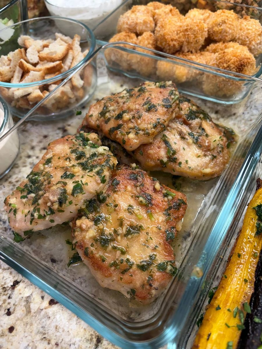 Garlic and parsley cling to seared pork loin chops, croutons and panko cauliflower behind them.