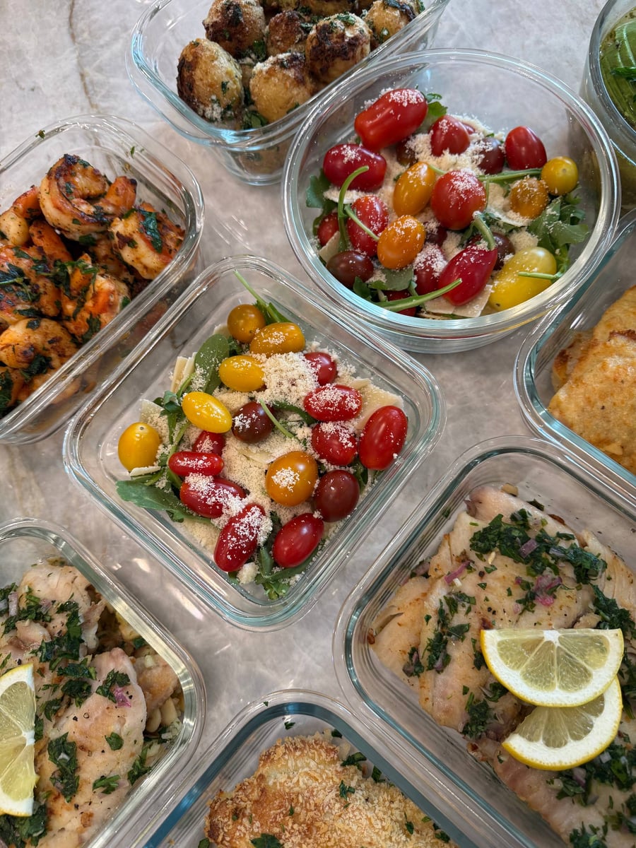 Paprika stains curled shrimp orange under chopped parsley, arugula tomato salads stacked to the right.