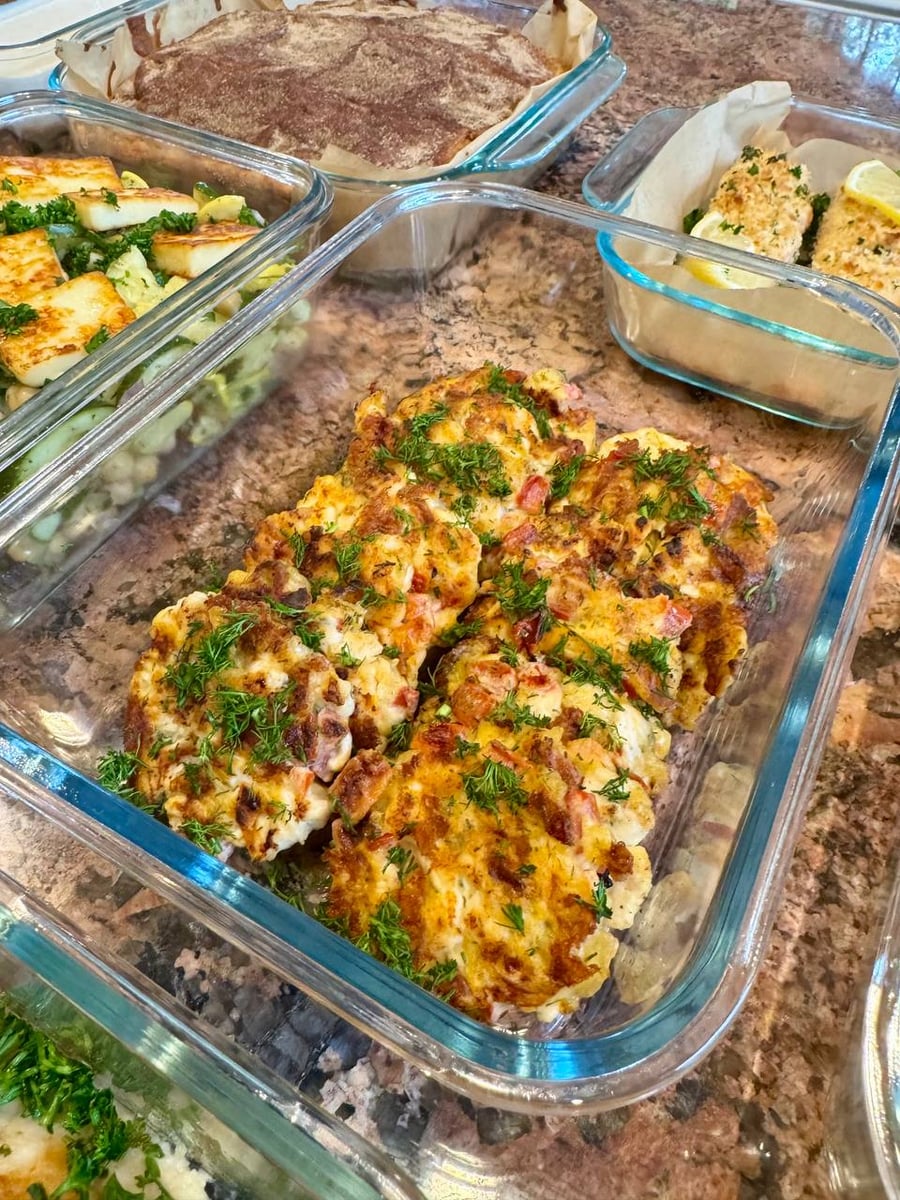 Dill and diced tomato freckle the browned chicken mozzarella patties, packed edge to edge in their baking dish.