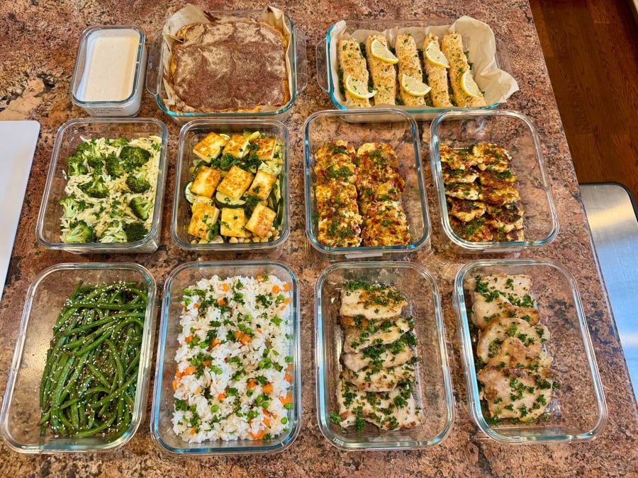 Eleven containers line up: panko salmon with lemon, dill chicken patties, broccoli orzo and cinnamon cake.