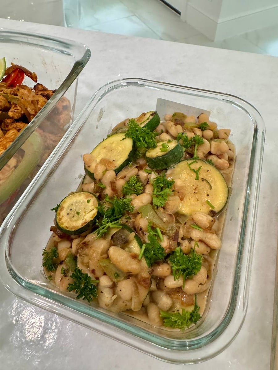 Curly parsley and zucchini coins sit over the braised white beans, fajita chicken in the next tray.
