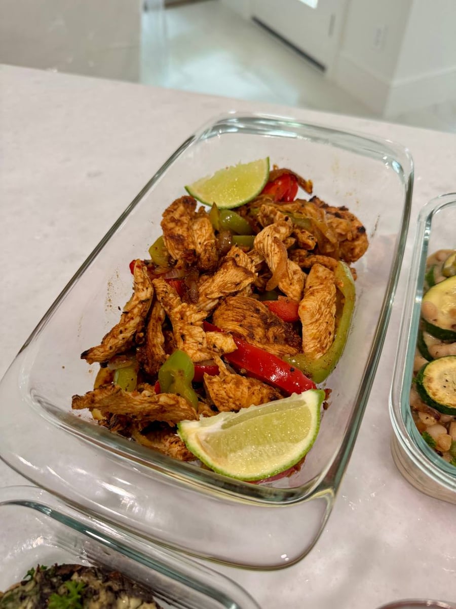 Lime wedges bracket the fajita chicken, red and green bell pepper strips folded all through it.