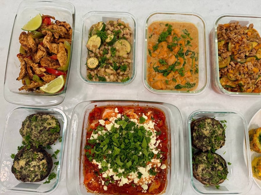 Nine containers seen from above: saganaki, fajita chicken, white beans, sweet potato stew, stuffed portobellos.