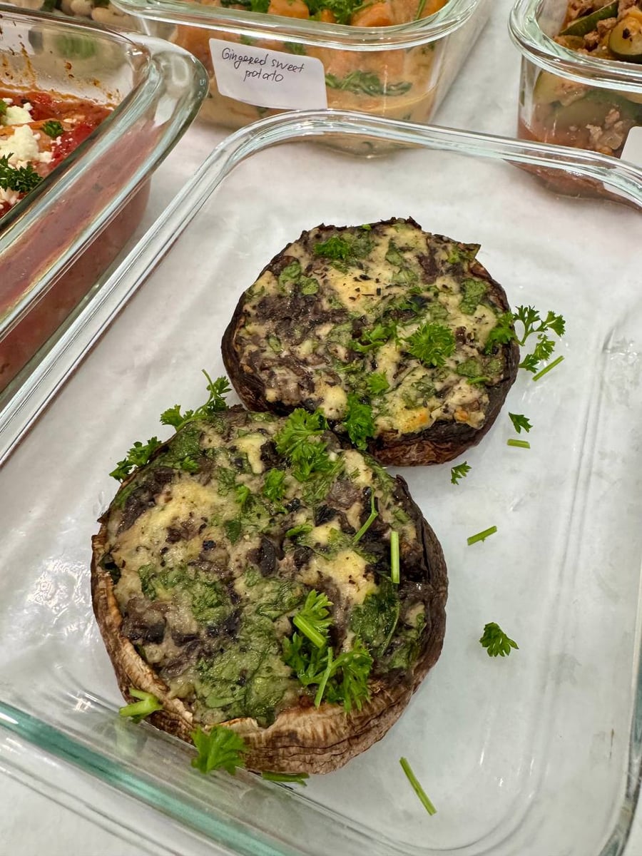 Melted parmesan and spinach fill two portobello caps, parsley scattered around them on the glass.