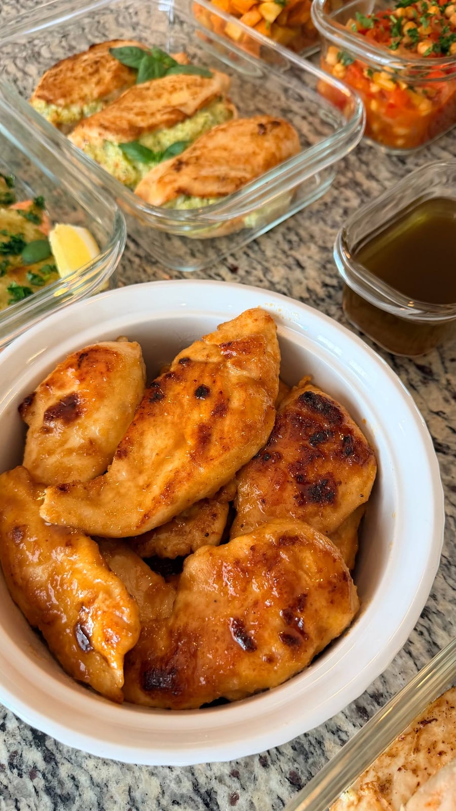 Sticky amber glaze coats chicken in a ridged white ramekin, char marks showing on each piece.