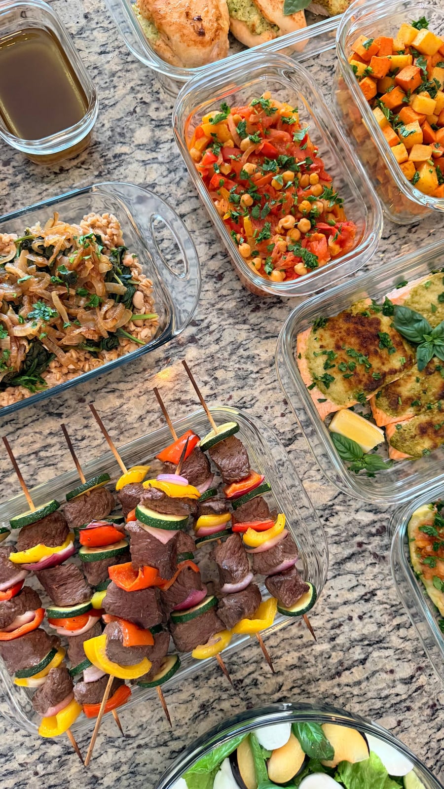 A pesto lid browns over salmon filets, lemon wedge and basil tucked at the edge, kebobs alongside.