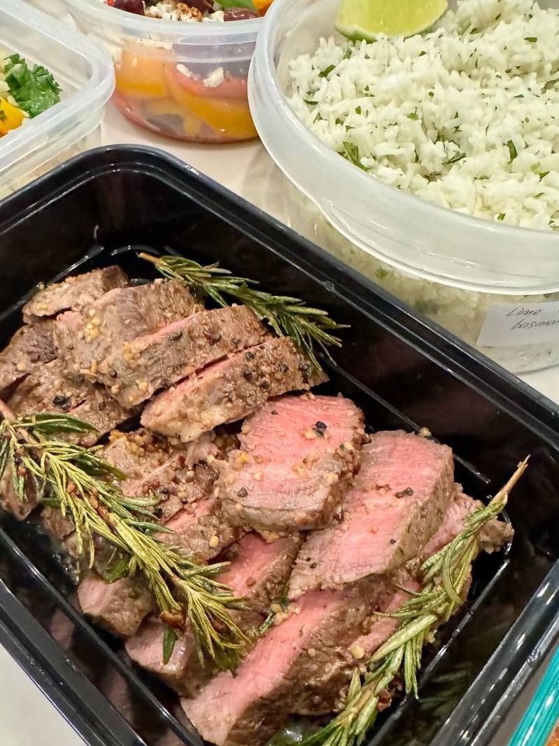 Two lime wedges sit in the cilantro basmati rice, rosemary filet mignon and Brussels sprouts around it.