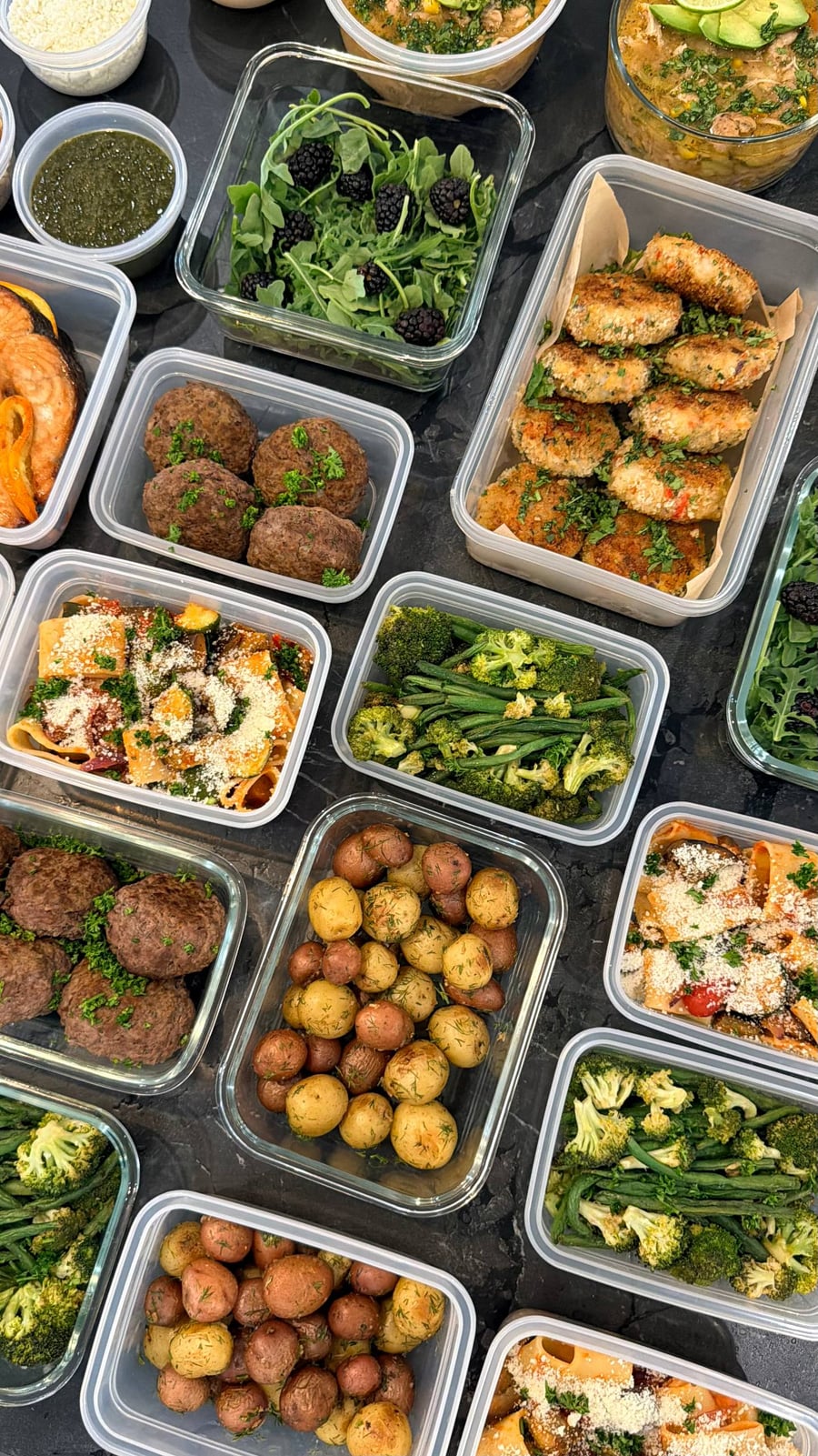 Parsley dots dense Greek beefsteaks of ground beef and feta, salmon steaks and veggie pasta beside them.