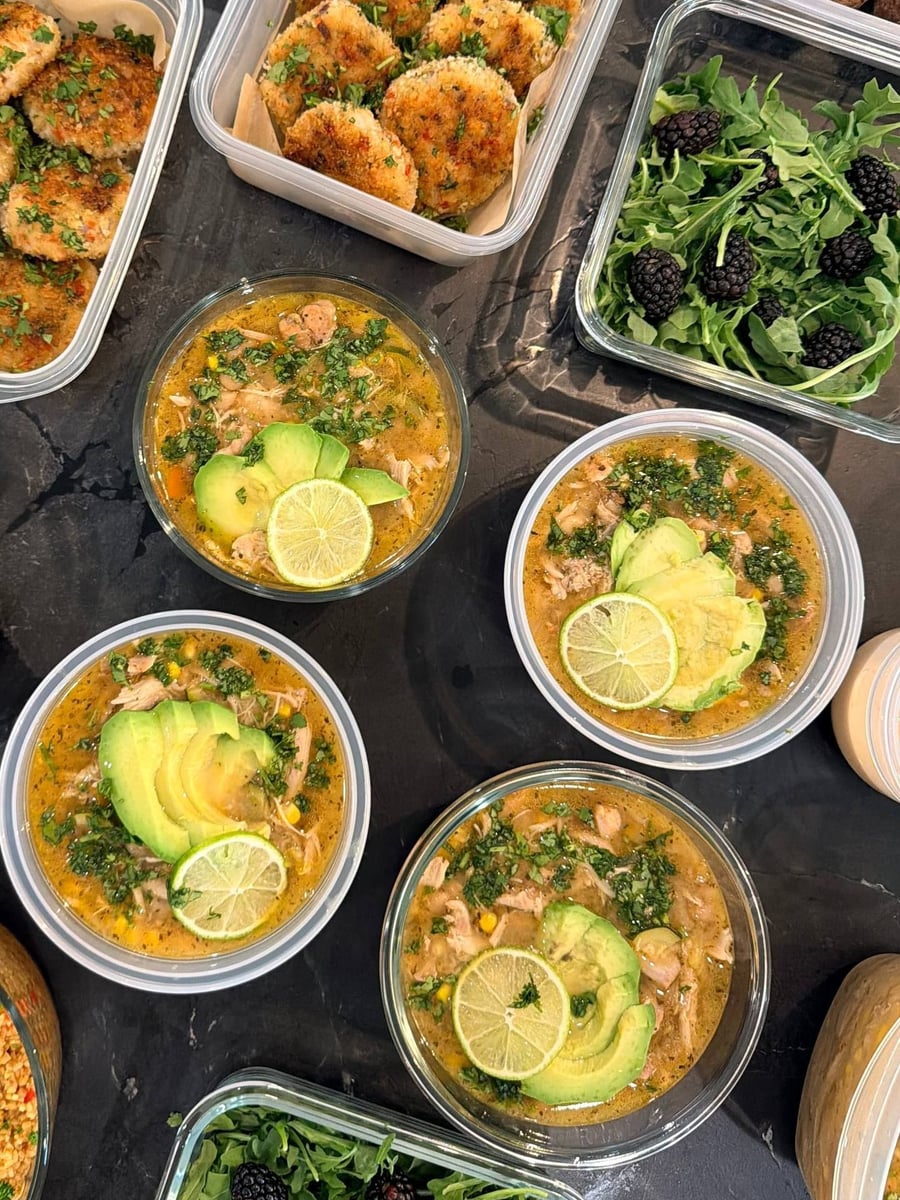 Avocado fans and a lime wheel float on shredded chicken salsa verde soup across four round bowls.