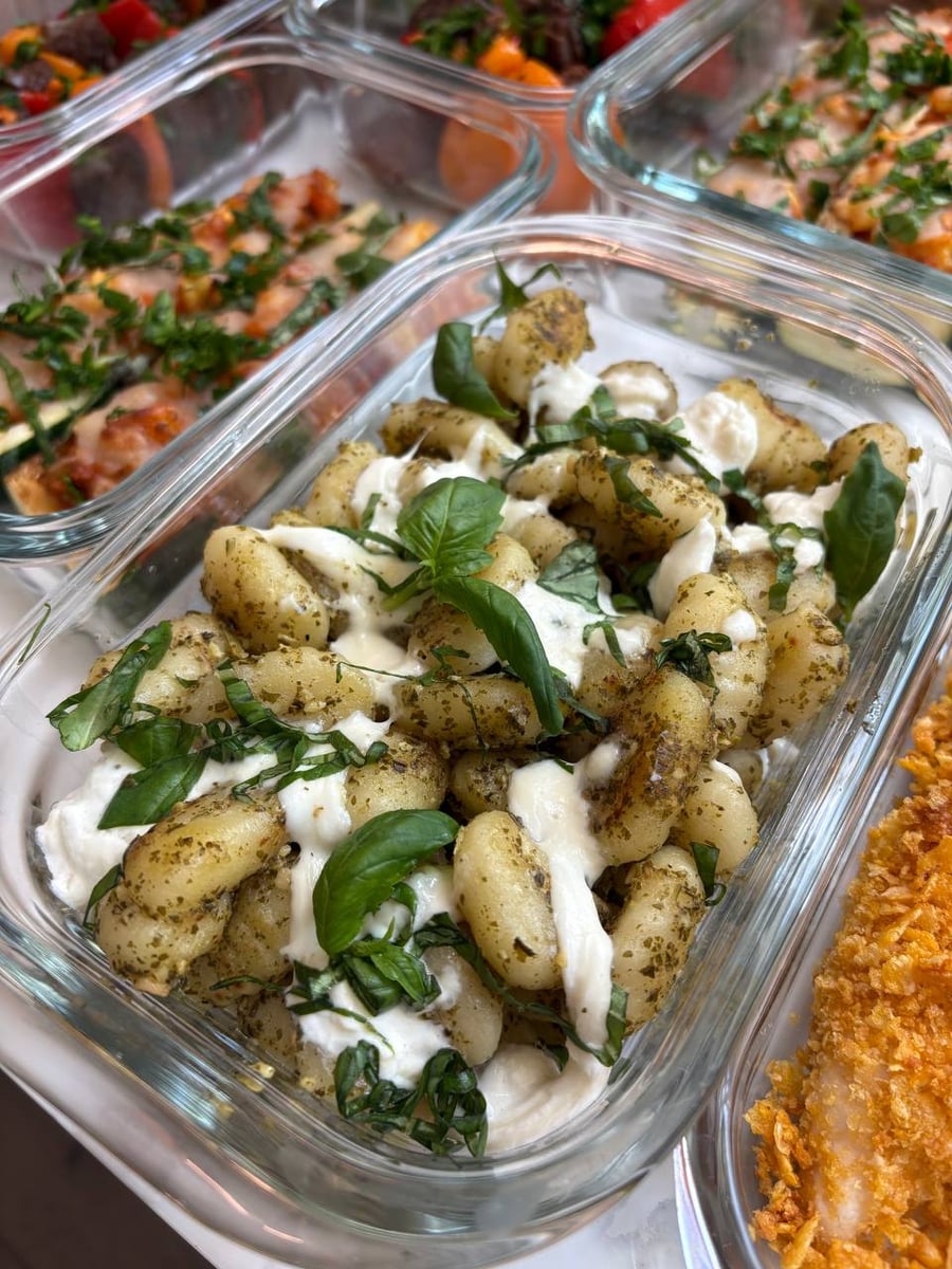 Fourteen dishes fill the counter, from cornflake crusted tenders and pesto gnocchi to zucchini boats and plum salad.