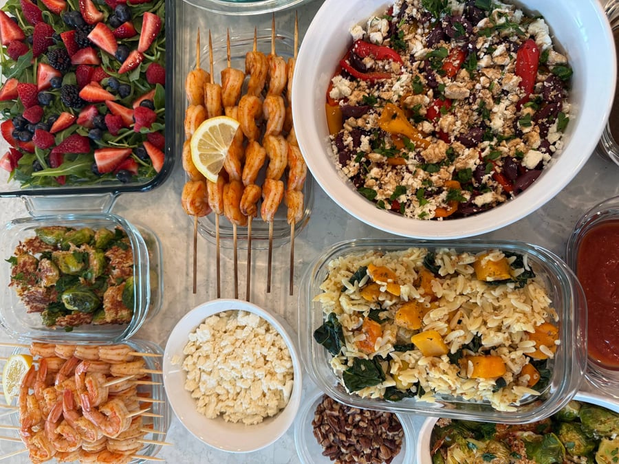 General Tso chicken bites glisten beside sliced rosemary filet, pecan salmon, shrimp skewers and berry salad.